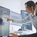 Two cybersecurity experts analyzing computer code to fix a chrome memory vulnerability leak